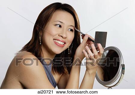 Woman applying eye shadow, looking at compact View Large Photo Image Stock Image - Woman applying eye shadow, looking at compact. Fotosearch