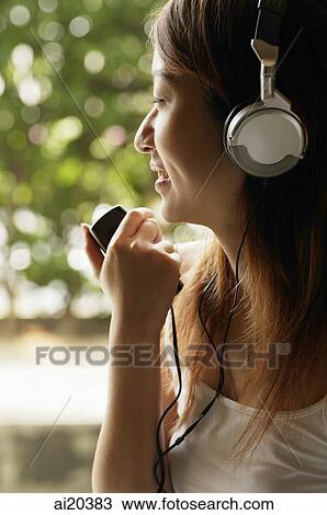 Woman listening to MP3 player, smiling View Large Photo Image Stock Image - Woman listening to MP3 player, smiling. Fotosearch