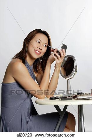 Woman looking at compact mirror, applying eyeshadow View Large Photo Image Stock Image - Woman looking at compact mirror, applying eyeshadow. Fotosearch