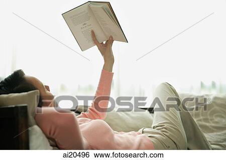 Woman lying on sofa, reading a book View Large Photo Image Stock Photograph - Woman lying on sofa, reading a book. Fotosearch