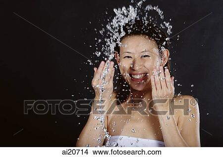 Woman splashing her face with water, smiling View Large Photo Image Picture - Woman splashing her face with water, smiling. Fotosearch