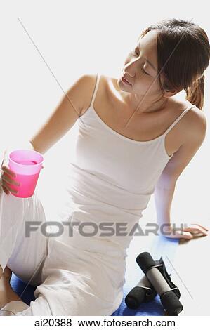 Woman with glass of water in one hand, sitting on floor, leaning back View Large Photo Image Stock Photo - Woman with glass of water in one hand, sitting on floor, leaning back. Fotosearch