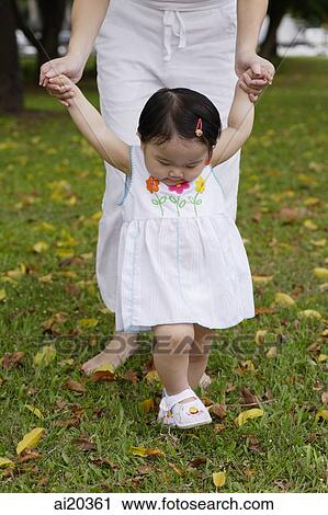 Young girl in park with mother, walking on grass View Large Photo Image Stock Image - Young girl in park with mother, walking on grass. Fotosearch