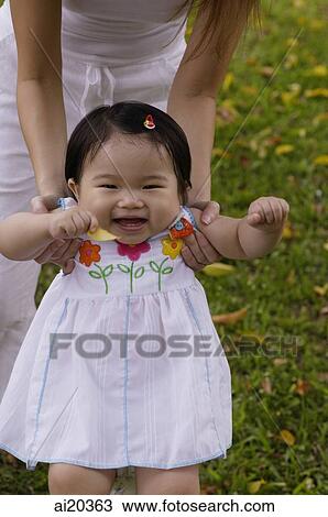 Young girl standing, being supported by her mother View Large Photo Image Stock Image - Young girl standing, being supported by her mother. Fotosearch