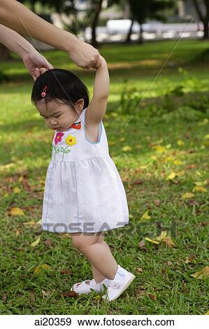 Young girl walking, mother holding her hands, guiding her View Large Photo Image Stock Photo - Young girl walking, mother holding her hands, guiding her. Fotosearch