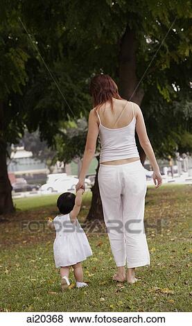 Young girl walking with mother in park View Large Photo Image Stock Photo - Young girl walking with mother in park. Fotosearch