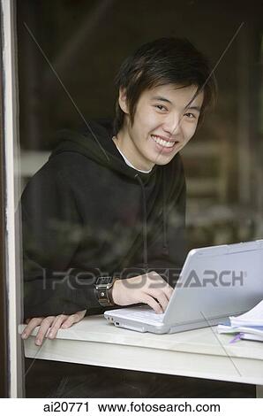 Young man using laptop, smiling at camera View Large Photo Image Stock Image - Young man using laptop, smiling at camera. Fotosearch