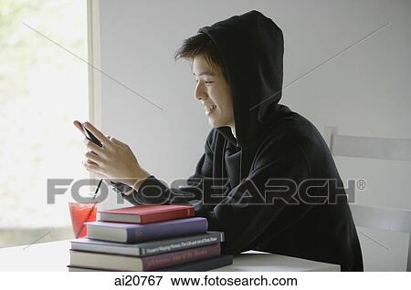 Young man with hooded jacket, looking at mobile phone View Large Photo Image Stock Photo - Young man with hooded jacket, looking at mobile phone. Fotosearch
