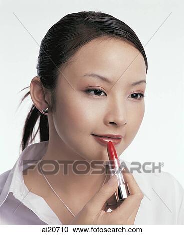 Stock Image - Young woman applying lipstick. Fotosearch