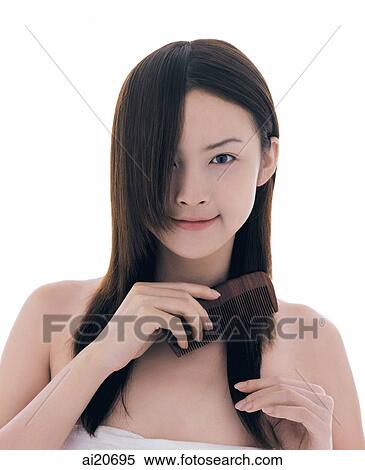 Young woman combing her hair, looking at camera View Large Photo Image Stock Photography - Young woman combing her hair, looking at camera. Fotosearch