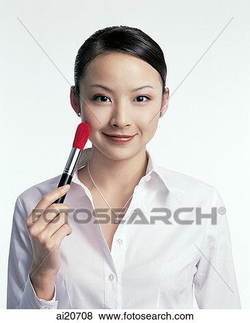 Young woman holding make-up brush to cheek View Large Photo Image Stock Photo - Young woman holding make-up brush to cheek. Fotosearch