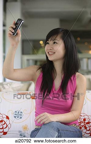 Young woman holding mobile phone, taking a picture of herself View Large Photo Image Stock Image - Young woman holding mobile phone, taking a picture of herself. Fotosearch