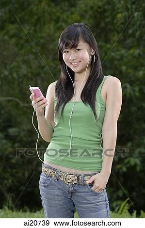 Young woman in green tank top and jeans listening to MP3 player View Large Photo Image Stock Photo - Young woman in green tank top and jeans listening to MP3 player. Fotosearch