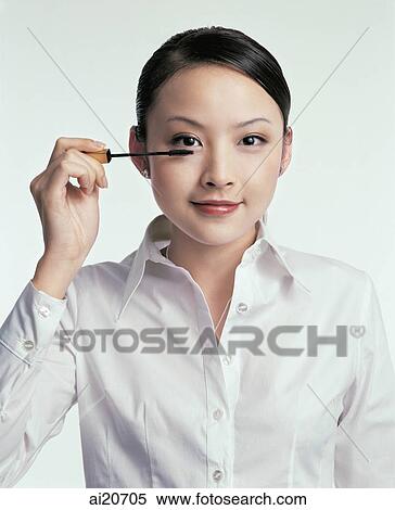 Young woman looking at camera, applying mascara View Large Photo Image Stock Photography - Young woman looking at camera, applying mascara. Fotosearch