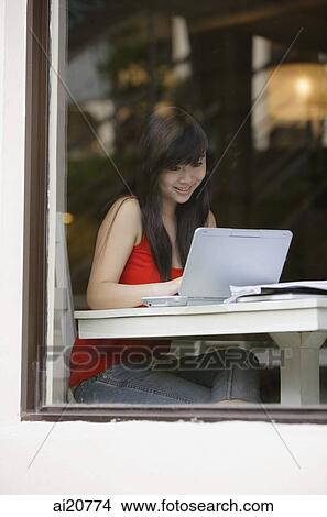 Young woman sitting at table, using laptop View Large Photo Image Picture - Young woman sitting at table, using laptop. Fotosearch