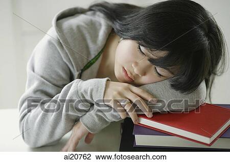 Stock Image - Young woman sleeping on stack of books. Fotosearch