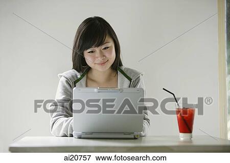 Young woman using laptop, drink on table next to her View Large Photo Image Stock Photo - Young woman using laptop, drink on table next to her. Fotosearch