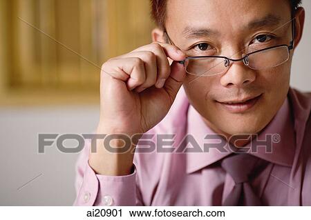 Businessman adjusting glasses, looking at camera View Large Photo Image Stock Image - Businessman adjusting glasses, looking at camera. Fotosearch