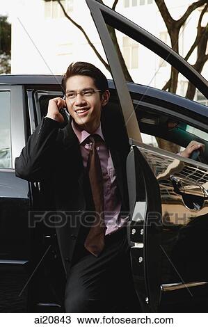 Businessman getting out of car, on the phone View Large Photo Image Stock Image - Businessman getting out of car, on the phone. Fotosearch
