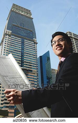 Businessman holding blueprint View Large Photo Image Stock Photography - Businessman holding blueprint. Fotosearch