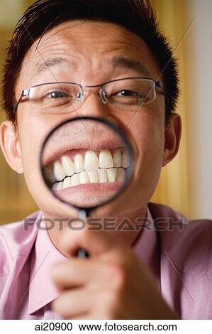 Businessman holding magnifying glass, focus on teeth View Large Photo Image Stock Image - Businessman holding magnifying glass, focus on teeth. Fotosearch