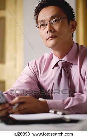 Businessman holding mobile phone, looking away View Large Photo Image Stock Photo - Businessman holding mobile phone, looking away. Fotosearch