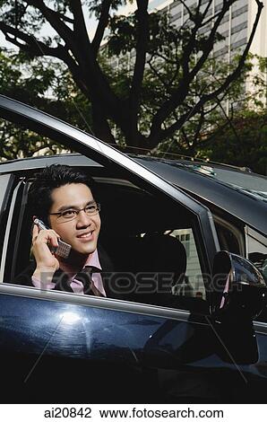 Businessman in car, using mobile phone, city location View Large Photo Image Stock Image - Businessman in car, using mobile phone, city location. Fotosearch