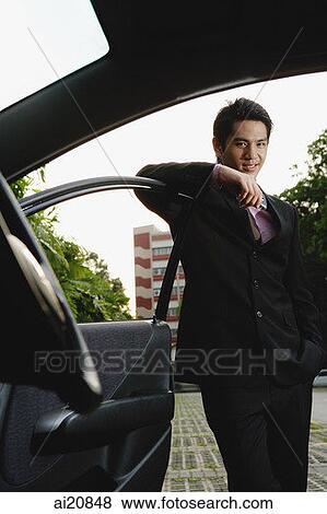 Businessman leaning on car door View Large Photo Image Stock Photo - Businessman leaning on car door. Fotosearch