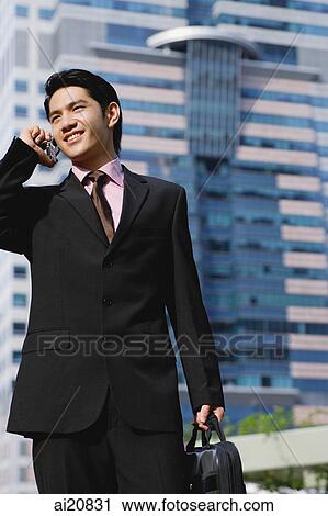 Businessman on mobile phone, carrying briefcase View Large Photo Image Stock Image - Businessman on mobile phone, carrying briefcase. Fotosearch