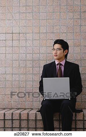Businessman sitting with laptop, looking away View Large Photo Image Stock Photo - Businessman sitting with laptop, looking away. Fotosearch