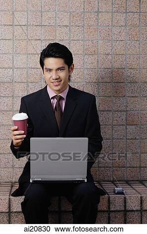 Businessman with laptop, looking at camera, holding coffee cup View Large Photo Image Stock Image - Businessman with laptop, looking at camera, holding coffee cup. Fotosearch