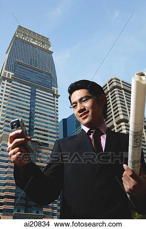 Businessman with mobile phone and blueprint View Large Photo Image Picture - Businessman with mobile phone and blueprint. Fotosearch