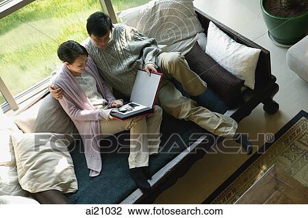 Couple at home looking a photo album View Large Photo Image Stock Image - Couple at home looking a photo album. Fotosearch