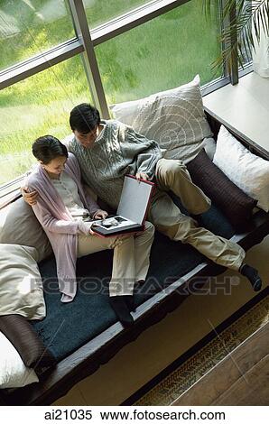 Couple at home looking a photo album, high angle view View Large Photo Image Stock Photography - Couple at home looking a photo album, high angle view. Fotosearch