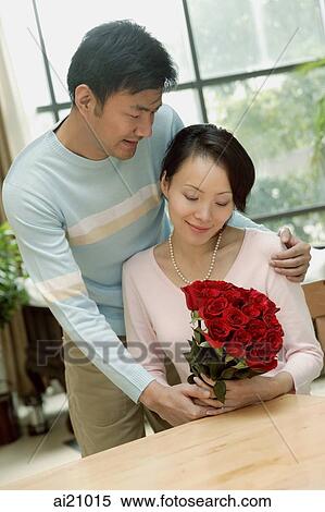 Stock Photography - Couple at home, man giving woman bouquet of roses. Fotosearch