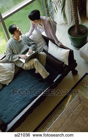 Couple at home, man using laptop, woman next to him View Large Photo Image Stock Photograph - Couple at home, man using laptop, woman next to him. Fotosearch