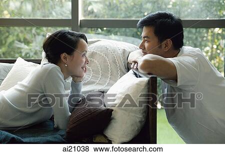 Couple at home, woman lying on sofa, looking at man View Large Photo Image Stock Photo - Couple at home, woman lying on sofa, looking at man. Fotosearch
