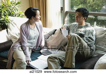 Couple in living room, looking at documents View Large Photo Image Stock Photo - Couple in living room, looking at documents. Fotosearch