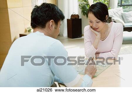 Couple in living room playing chess View Large Photo Image Stock Photograph - Couple in living room playing chess. Fotosearch