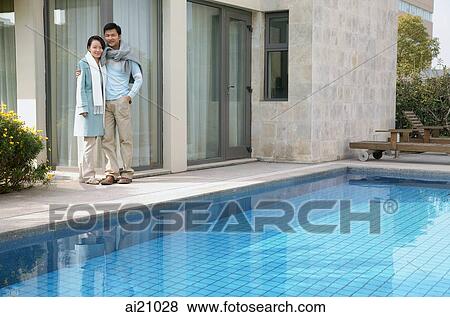 Couple standing outside house, next to swimming pool View Large Photo Image Stock Photo - Couple standing outside house, next to swimming pool. Fotosearch