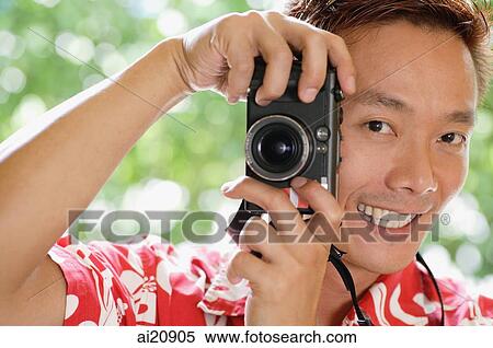 Man holding a camera, smiling View Large Photo Image Stock Photography - Man holding a camera, smiling. Fotosearch