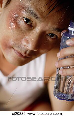 Man holding bottle of water to forehead, looking at camera View Large Photo Image Stock Photo - Man holding bottle of water to forehead, looking at camera. Fotosearch