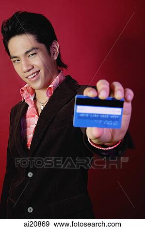 Stock Photo - Man holding credit card towards camera. Fotosearch