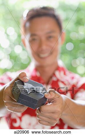 Man holding gift towards camera View Large Photo Image Stock Photograph - Man holding gift towards camera. Fotosearch