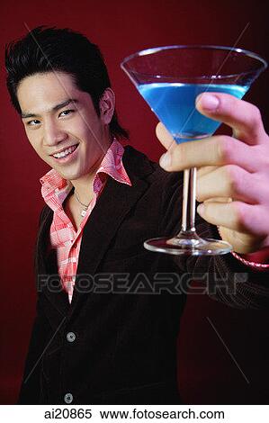 Stock Photography - Man holding up cocktail glass. Fotosearch