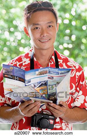 Stock Photo - Man in floral shirt holding a map, looking at camera. Fotosearch