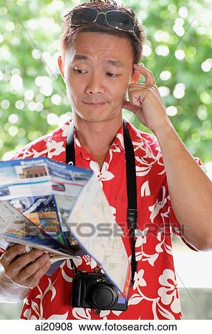 Man in floral shirt holding a map, scratching head View Large Photo Image Stock Photo - Man in floral shirt holding a map, scratching head. Fotosearch