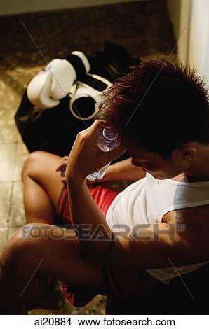 Picture - Man sitting down, hand on head. Fotosearch