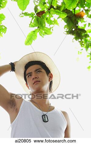 Stock Photography - Man wearing hat, hand on head, looking away. Fotosearch