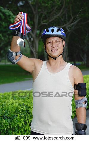 Mature adult wearing helmet, holding up medal View Large Photo Image Stock Photo - Mature adult wearing helmet, holding up medal. Fotosearch